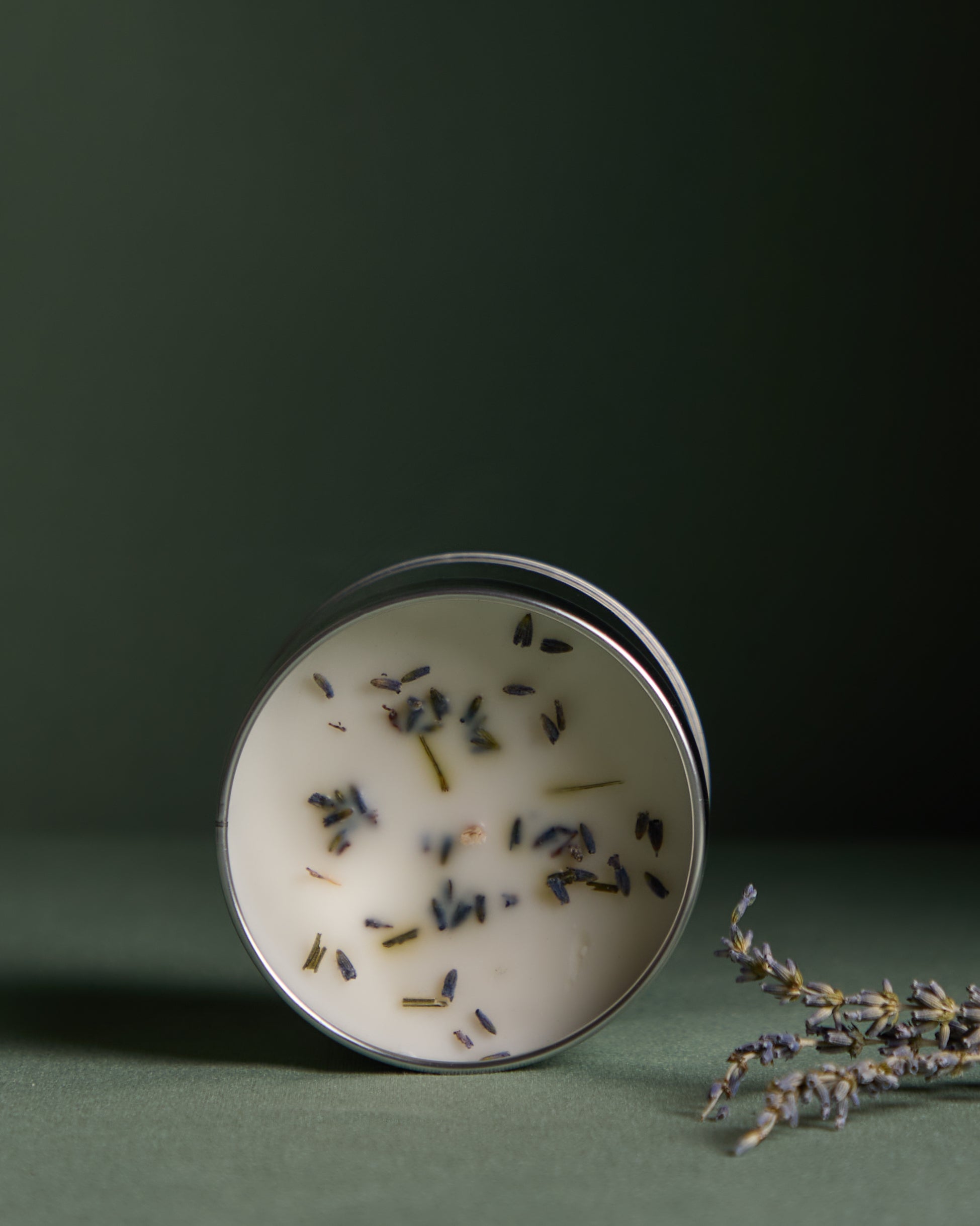Small round container with lavender petals on a dark green background