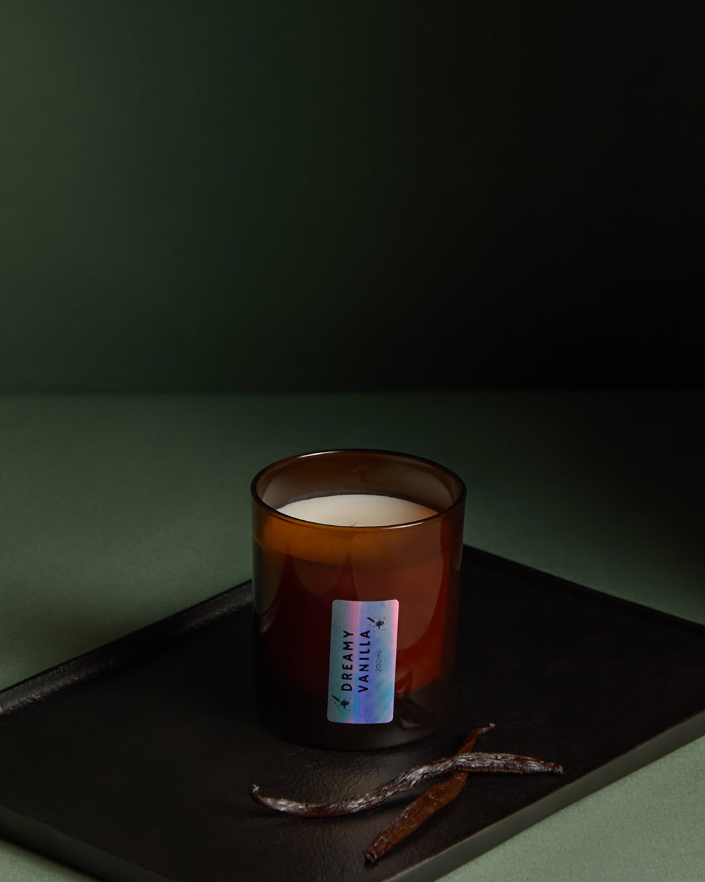 Candle in an amber glass jar with a label on a dark surface