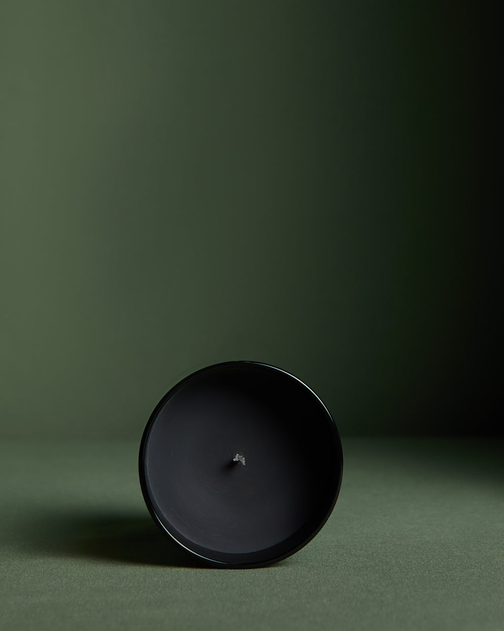 Close up view of Luxury hand poured soy wax candle in a black glass jar with black wax, wooden lid and fabric wick, finished with holographic silver label